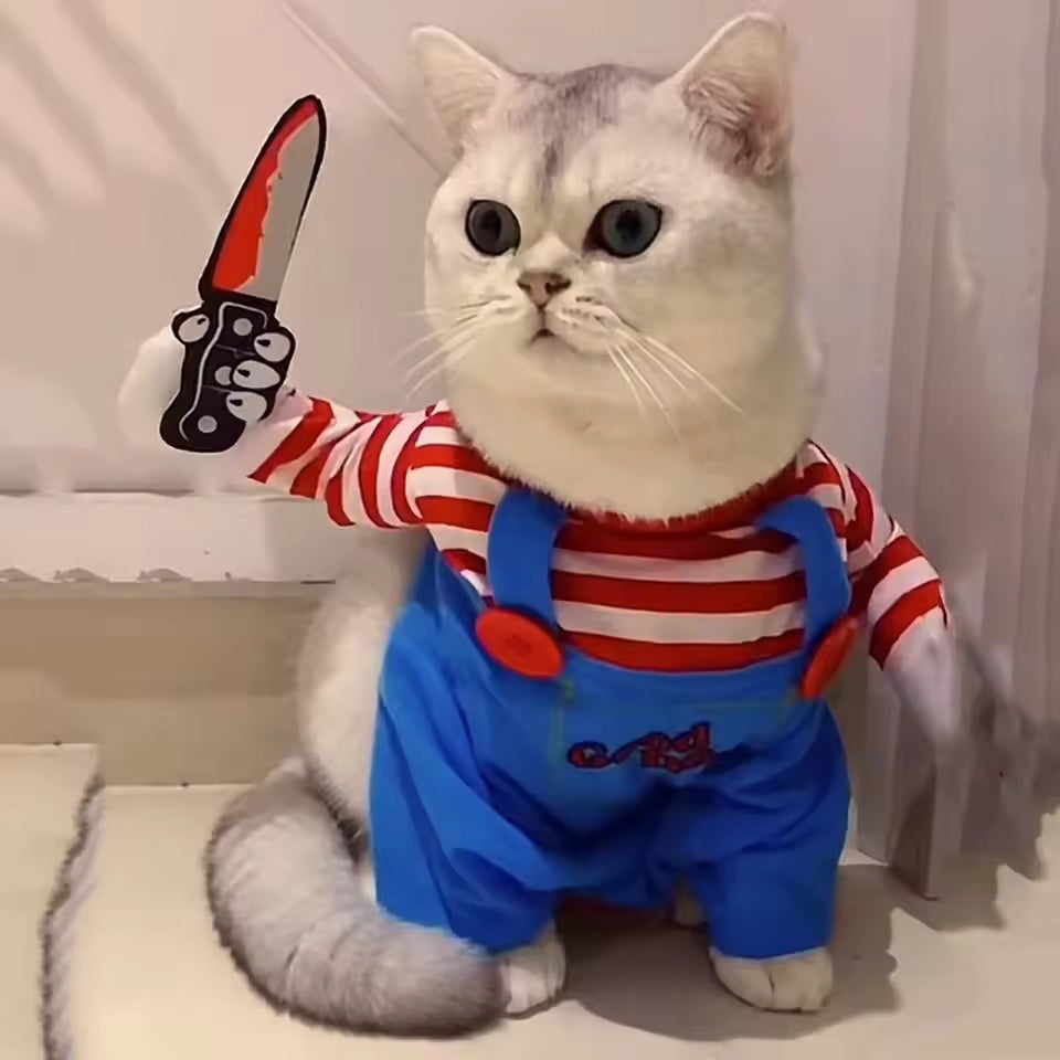 White cat wearing the killer doll costume with striped sleeves, blue overalls and prop knife